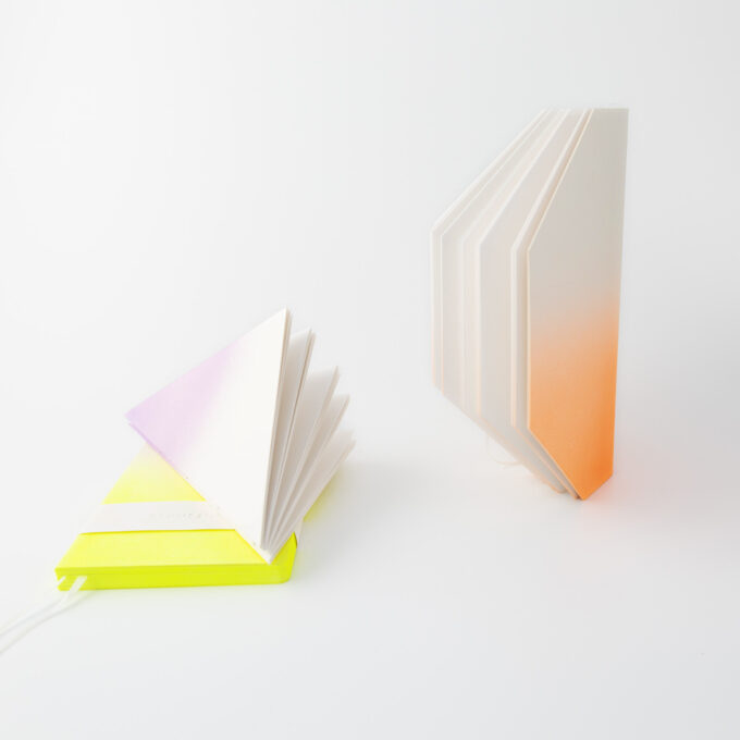 Anteckningsböcker i olika geometriska former i lysande färger, stående eller liggande.