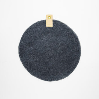 Rund dyna i ull med läderdetalj.