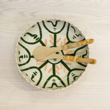 Salladsbestick i trä placerade i en handmålad keramikskål.