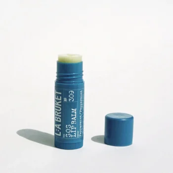 Läppbalsam med uppskruvat lock och synligt, cremefärgat cerat.